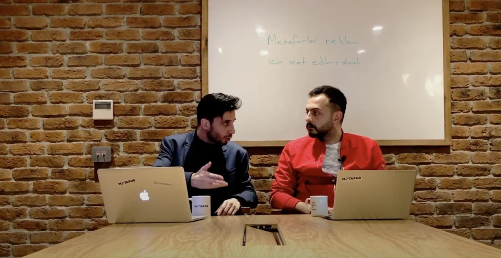 Metafor ekibi tuğla duvarlı ofiste beyaz tahta önünde strateji çalışmasında